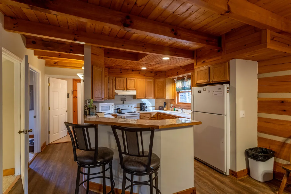 A warm, inviting kitchen with wooden cabinetry and a central island, ready for family cooking and socializing. The open doorway hints at a seamless flow between spaces, supporting active, communal living.